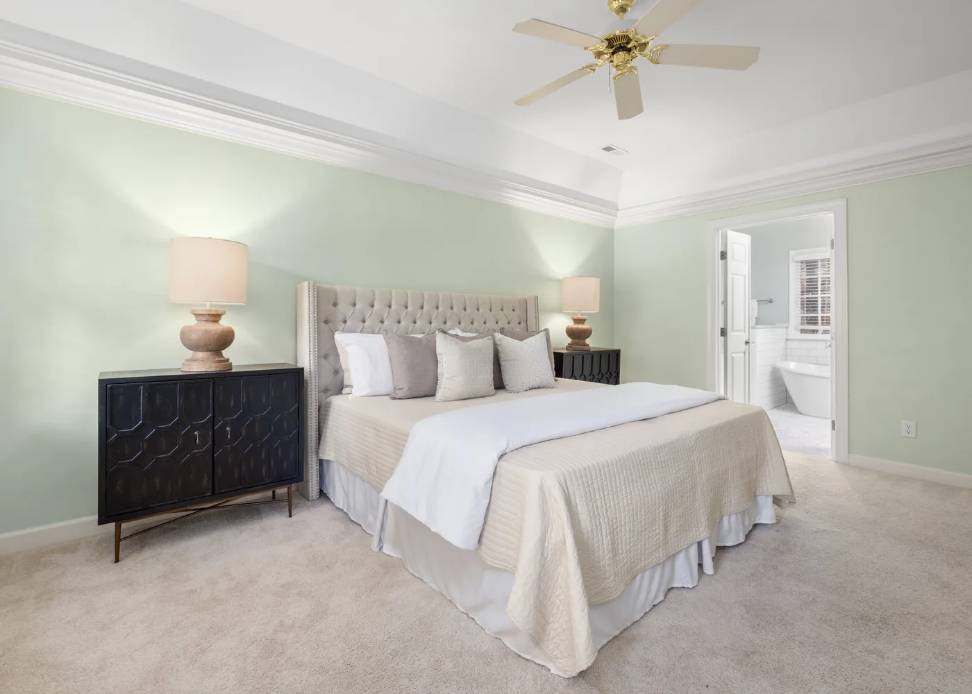 Sage-green bedroom with a neatly made cream bed and matching bedside lamps