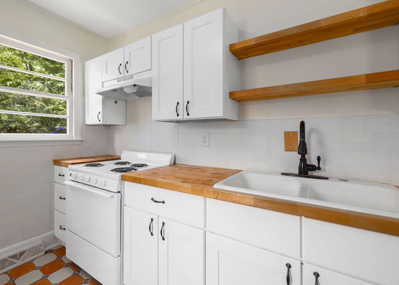 White kitchen with timber worktops, open wooden shelves and a farmhouse sink